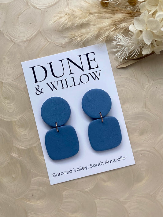 Blue dangle earrings on a Dune & Willow branded card. .
