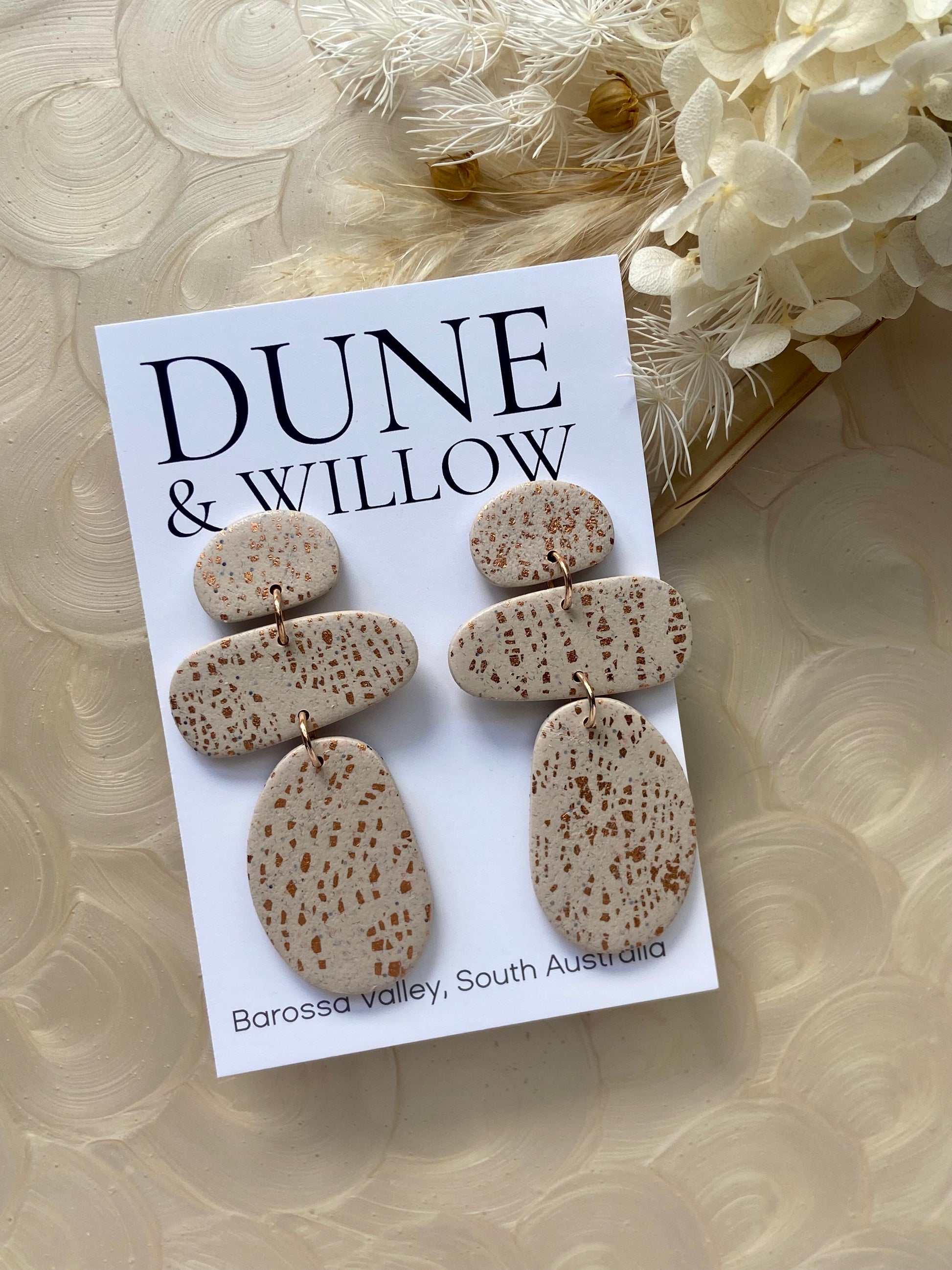 Dune & Willow earrings on a branded card with decorative flowers in the background