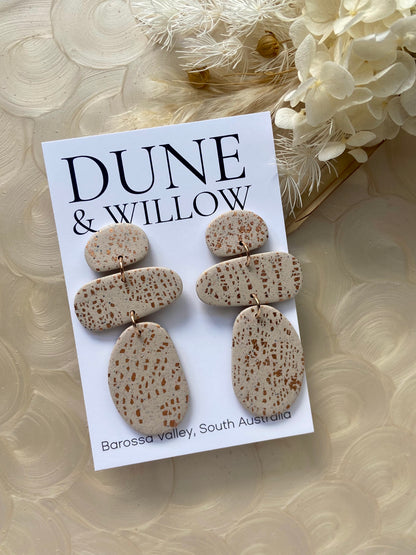 Dune & Willow earrings on a branded card with decorative flowers in the background